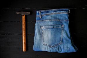 ein Paar von Jeans und ein Hammer auf ein schwarz Hintergrund foto