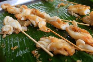 Tintenfisch Eier gegrillt auf Banane Blatt. Meeresfrüchte auf Straße Essen im Thailand foto
