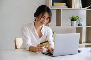 Frau genießen mit online Einkaufen Anwendung und suchen beim Laptop zum füllen Anerkennung Karte Nummer zu Zahlung. foto
