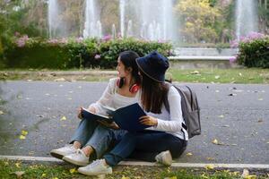 zwei Studenten sind Sitzung im Universität während lesen ein Buch und Kommunikation. lernen, Ausbildung, Universität, Hochschule, Absolvent Konzept. foto