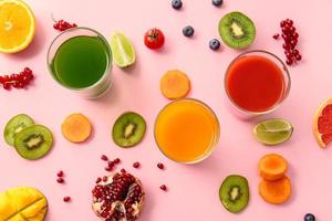 Gläser mit gesundem Saft, Obst und Gemüse auf farbigem Hintergrund foto