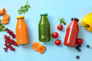 Flaschen mit gesundem Saft, Obst und Gemüse auf farbigem Hintergrund foto