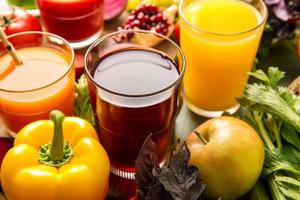 Gläser mit gesundem Saft, Obst und Gemüse auf farbigem Holzhintergrund foto