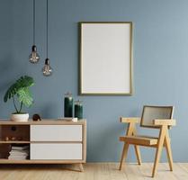 Postermodell mit vertikalen Rahmen an leerer dunkelblauer Wand im Wohnzimmer mit Sessel. foto
