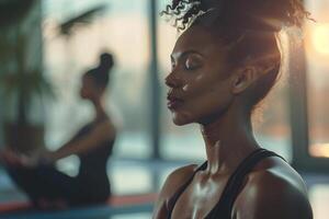 jung Frauen Sitzung und meditieren mit Augen geschlossen. verschwommen Yoga Studio auf Hintergrund. foto