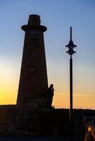 ein Mann Stehen und Rauchen durch das Leuchtturm von Kyrenia Hafen beim das Blau Stunde im Zypern foto