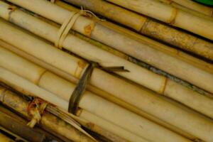 Hintergrund Fotografie. texturiert Hintergrund. ein Stapel von Trauben von alt Gelb Bambus. alt Bambus ist gesammelt auf das Seite von das Straße zum Gebäude Konstruktion. Bandung, Indonesien foto
