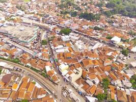 Antenne Aussicht von Main Straße von Westen Java Provinz, Indonesien. das Main Straße im das Mitte von Wohn Bereiche. Motorräder, Autos und elektrisch Fahrzeuge der Verkehr auf das Main Straße. Schuss von ein Drohne fliegend foto