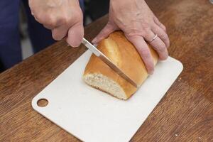 Schnitt das Laib mit ein Messer. bereiten Frühstück. foto