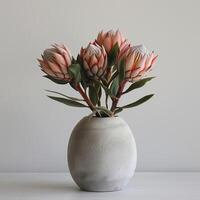 ein minimalistisch Beton Vase hält ein auffällig Protea Strauß. foto