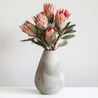 ein minimalistisch Beton Vase hält ein auffällig Protea Strauß. foto