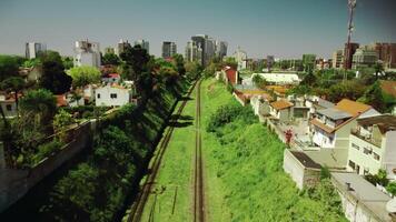 fliegend Über leeren Eisenbahn Schiene, Schiene Weg im Grün Gras unter Stadt Gebäude im Sommer, sonnig Tag. Buenos lüftet. foto