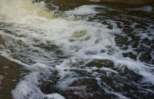 Wasserwellen des Flusses und des Meeres treffen bei Flut und Ebbe aufeinander. Tiefblaue stürmische Meerwasseroberfläche mit weißem Schaum und Wellenmuster, Hintergrundfoto foto