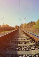 herbstliche Industrielandschaft. Eisenbahn, die sich zwischen grünen und gelben Herbstbäumen in die Ferne zurückzieht foto