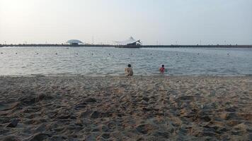 zwei Kinder spielen im das Wasser beim das Strand foto