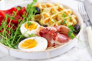 Englisch Frühstück. gekocht Ei, Schinken, Waffeln und Grün Kräuter. foto