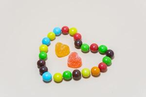 Herz geformt Süßigkeiten und multi farbig Süßigkeiten auf isoliert auf Weiß Hintergrund. foto