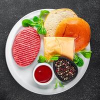 Burger einstellen roh Kotelett, Brötchen, Käse, Tomate Soße, Grüns frisch Kochen Vorspeise Mahlzeit Essen Snack auf das Tabelle Kopieren Raum Essen Hintergrund rustikal foto