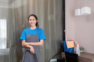 Reinigung Produkt, und Korb mit Frau asiatisch Mitarbeiter Reinigung Bedienung im Schlafzimmer zu sauber Bakterien beim Wohnung. Reiniger oder Maid mit Container zu Arbeit im Zimmer foto