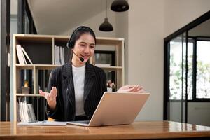 Anruf Center freundlich Frau asiatisch im Büro zum Kunde Service, technisch Unterstützung und Beratung, Kontakt und Kommunikation mit Mitarbeiter Operator im Hilfe Schreibtisch Agentur foto