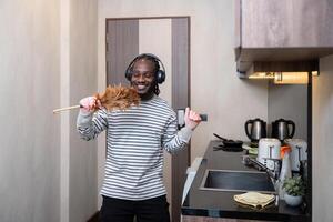 afrikanisch amerikanisch Mann Hören zu Musik- während Reinigung im Küche foto