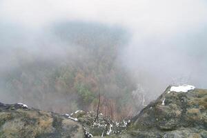 Aussicht von das groß zschirnstein in das Senke von bunt Nadelbäume durch Nebel foto