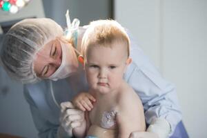 ein wenig Junge Krankenschwester Leckereien ein brennen. ein Kind im das Krankenhaus ist verletzt. das Arzt Leckereien das Baby. wenig Krankenhaus geduldig. foto