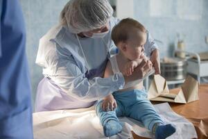 ein wenig Junge Krankenschwester Leckereien ein brennen. ein Kind im das Krankenhaus ist verletzt. das Arzt Leckereien das Baby. wenig Krankenhaus geduldig. foto