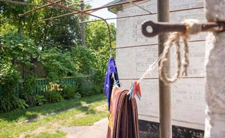 Plastikwäscheklammern hängen in einer Reihe am Seil. Seil im Freien, auf einem unscharfen Hintergrund in einem sonnigen Garten. Wäscheleine auf der Straße. Wäscheklammern. foto