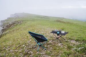 Wandern Küche Camping Ausrüstung steht auf das Berg gegen das Hintergrund von Natur, ein falten Camping Stuhl, Camping Möbel. foto