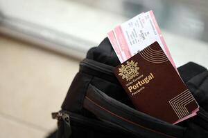 rot Portugal Reisepass von europäisch Union mit Fluggesellschaft Tickets auf touristisch Rucksack foto