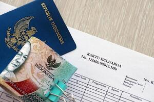Kartu keluarga Familie Identität Karte mit indonesisch Reisepass und Bündel von indonesisch Rupiah Rechnungen foto