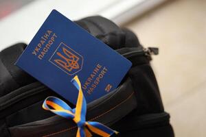 ukrainisch biometrisch Reisepass auf schwarz touristisch Rucksack mit ukrainisch Band foto