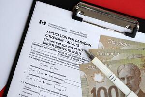Anwendung zum kanadisch Staatsbürgerschaft zum Erwachsene auf Tabelle mit Stift und Dollar Rechnungen foto