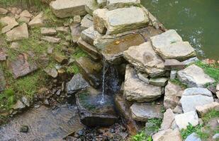 schließen oben von ein klein Wasserfall verschütten Über Moos bedeckt Felsen im regional Park. handgemacht Fluss Wasserfall foto