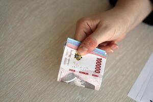 weiblich Buchhalter Hand geben Bündel von viele indonesisch Rupiah Geld Rechnungen von Neu Serie foto