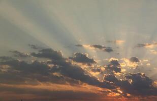 schön Sonnenaufgang mit warm Orange Sonnenlicht und Balken durch Blau Himmel foto