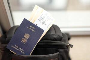 Blau indisch Reisepass mit Fluggesellschaft Tickets auf touristisch Rucksack foto
