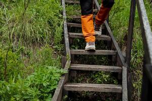 Wandern Schuhe, hölzern Treppe im Natur, Nahansicht Füße, Gehen Schritte im das Wald, Trekking Schuhe, wandern. foto