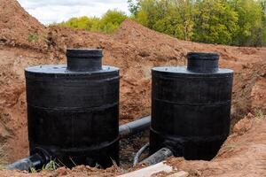 das schwarz Gut ist gemalt mit Abdichtung, ein Beton Also, ein Wasser Rohr im das Grube, das Konstruktion von Kanalisation, das Verlegung von Propylen Rohre, pvc Rohr, verstärkt Beton im das Ring. foto