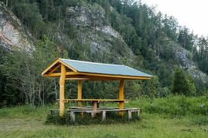 Tabelle im das Campingplatz mit ein Überdachung von das Regen, ein Platz zu entspannen im Natur, ein Parkplatz Menge ausgestattet im das Wald, ein Tourist Camping unter das Berg. foto