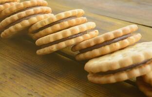 Ein runder Sandwichkeks mit Kokosfüllung liegt in großen Mengen auf einer braunen Holzoberfläche. Foto von essbaren Leckereien auf einem hölzernen Hintergrund mit Kopierraum