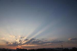 schön Sonnenaufgang mit warm Orange Sonnenlicht und Balken durch Blau Himmel foto