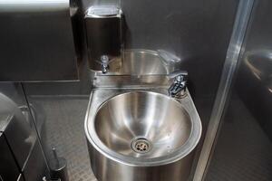 rostfrei Stahl Metall Waschbecken, Seife Spender, klein Wasserhahn, Hand Waschbecken, Anti-Vandalismus Waschbecken, Öffentlichkeit Toilette im das Stadt. foto