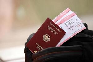 rot Deutsche Reisepass von europäisch Union mit Fluggesellschaft Tickets auf touristisch Rucksack foto