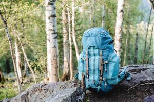 ein Tourist Rucksack steht auf das Boden, ein Blau Tasche zum Dinge, Sport Ausrüstung, ein Wanderung im das Berge, ein Schüssel zum Transport. foto