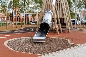 modern Kinder- Spielplatz zum draussen Spiele, ein rutschen Rohr gemacht von Metall, Pyramiden gemacht von Holz, Gummi Glasur auf das Spielplatz. foto