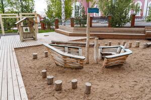 Kinder- Spielplatz zum Kinder, ein hölzern Schiff begraben im das Sand, ein Platz zum draussen Spiele, ein modern Kinder- Amüsement Park, ein Spielplatz gemacht von Bretter. foto