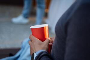 das Konzept von ein Papier Tasse zum heiß Getränke, das Hand hält ein rot betrachten, Einweg Teller, ein Becher zum heiß Kaffee, ein Kaffee Glas. foto