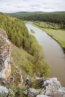 das Fluss fließt im das Senke von hügelig Berge, Frühling ist wolkig, kalt Sommer im Europa, üppig Vegetation von Wälder. foto